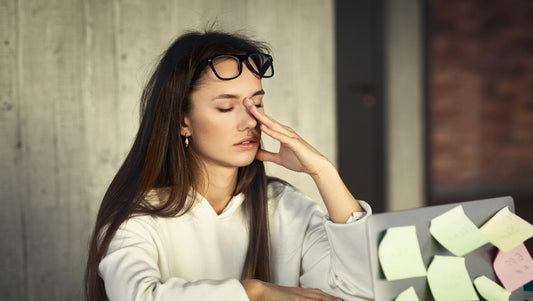 Müde junge Frau reibt sich die Augen vor ihrem Laptop – Trotz genügend Schlaf erschöpft und energielos.